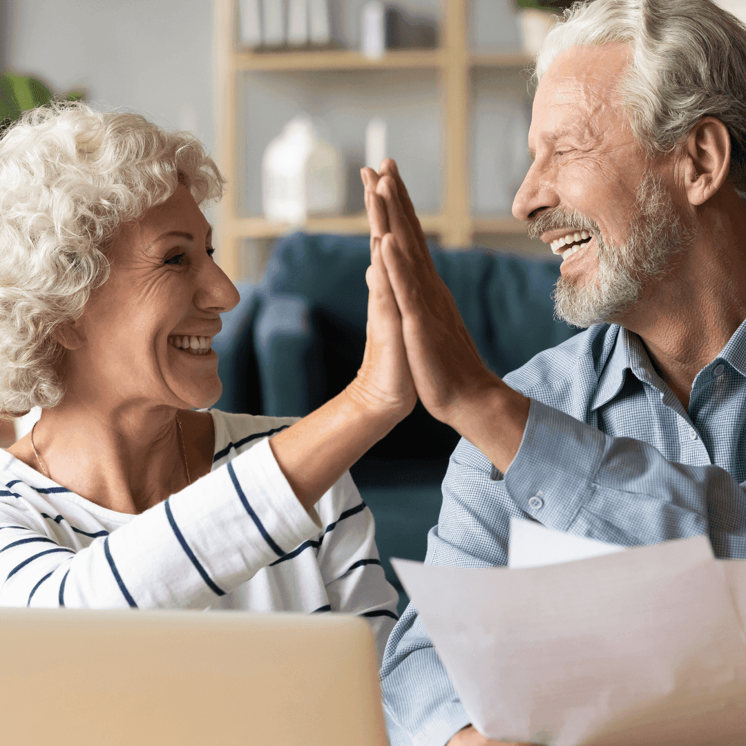 Couple living with early-stage Alzheimer’s sharing a joyful high five — representing MiM (Memory in Motion), an app that supports Travelers and their Supporters with daily routines, empathy, and real-life coordination.
